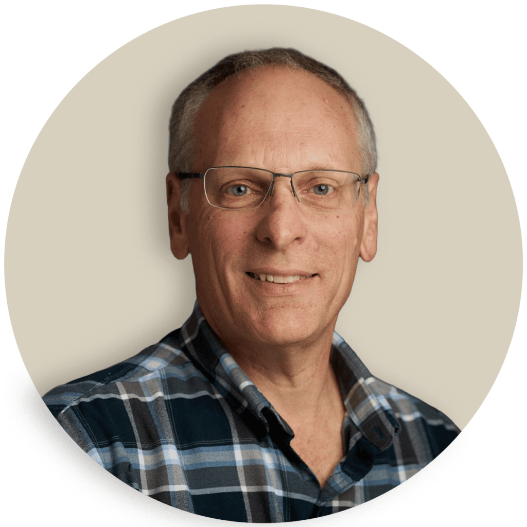 Portrait of Mark Mangano wearing glasses and a plaid shirt